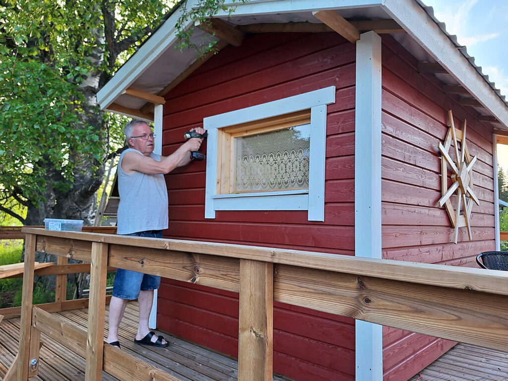 Mies ruuvaa saunalautan ikkunanpieltä.