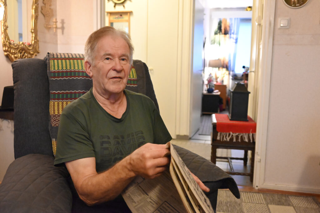 Mieshenkilö istuu nojatuolissa käsissään sanomalehti