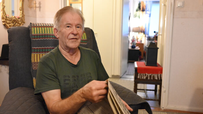 Mieshenkilö istuu nojatuolissa käsissään sanomalehti