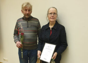 Kaksi henkilöä seisoo rinnakkain, toisella kädessään kunniakirja