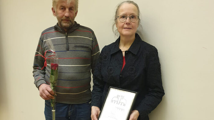 Kaksi henkilöä seisoo rinnakkain, toisella kädessään kunniakirja