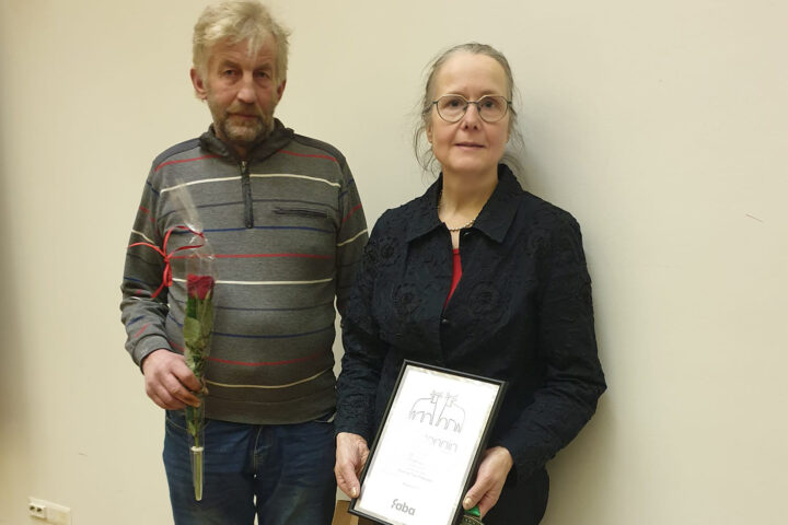 Kaksi henkilöä seisoo rinnakkain, toisella kädessään kunniakirja